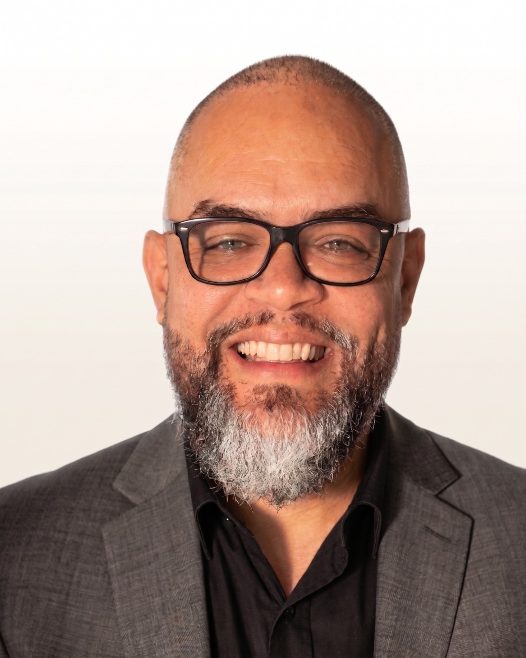 Gabriel Reynoso, AI systems architect, smiling in a charcoal blazer and glasses: Orlando, Florida